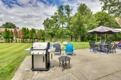 a backyard with a grill and chairs and tables at Waterfront Wallkill Duplex Home with Fire Pits! in Wallkill