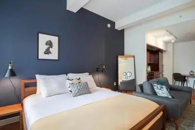 a bedroom with a large bed and a blue wall at FiDi Studio w Residents Bar Golf Simulator Gym NYC-271 in New York