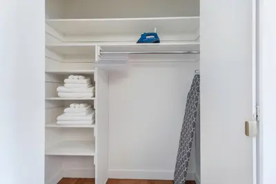 a closet with white towels on a shelf at FiDi Studio w Residents Bar Golf Simulator Gym NYC-271 in New York