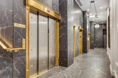a hallway with metal doors and marble walls at FiDi Studio w Residents Bar Golf Simulator Gym NYC-271 in New York