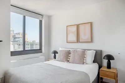 a white bedroom with a bed and a window at Tribeca Studio w Tons of light Gym Pool NYC-118 in New York