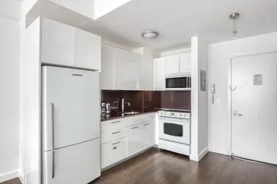 a kitchen with white cabinets and a refrigerator at UWS 1br w gym doorman nr Central Park NYC-1100 in New York
