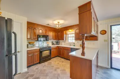 a kitchen with wooden cabinets and a black refrigerator at 10 Mi to Dtwn Lancaster Charming Home with Yard! in Leola