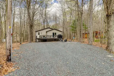a house in the middle of a road in the woods at Fire Pit and Deck Inviting Pocono Lake Home in Pocono Lake