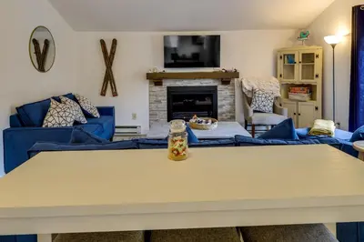 a living room with blue couches and a table at Fire Pit and Deck Inviting Pocono Lake Home in Pocono Lake