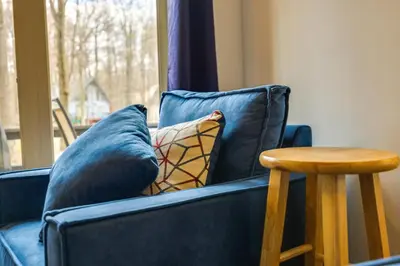 a blue couch with a pillow and a wooden table at Fire Pit and Deck Inviting Pocono Lake Home in Pocono Lake