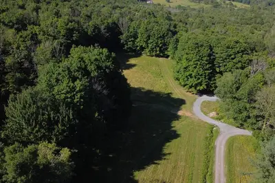 an aerial view of a winding road in a forest at Catskills Escape - Serenity on 105 Acres, 2 hours from NYC in Ellenville