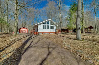 a house in the middle of a forest at Cozy Pocono Lake Cottage with Fire Pit and Ping Pong! in Pocono Lake