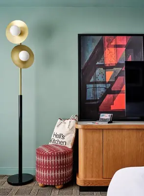 a bedroom with a lamp and a ottoman and a tv at Romer Hell's Kitchen in New York