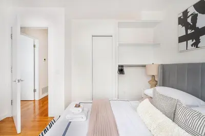 a white bedroom with a bed and a mirror at 13-3 I Brand New 4BR 3 Baths Duplex Private Roof Deck in New York