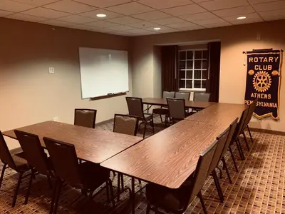 a conference room with tables and chairs and a whiteboard at Microtel Inn & Suites-Sayre, PA in Sayre