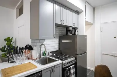 a kitchen with white cabinets and a stainless steel refrigerator at 74-1A New Studio in Prime UWS - GYM In Building in New York