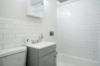 a white bathroom with a sink and a tub at 74-1A New Studio in Prime UWS - GYM In Building in New York