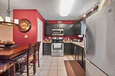 a kitchen with black cabinets and a red wall at Tannersville Tranquility in Tannersville