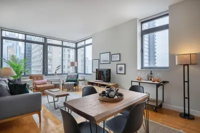 a living room with a table and chairs and windows at Modern Bright Times Sq 1BR w Indoor pool NYC-8 in New York