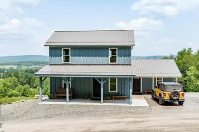 a blue house with a yellow jeep parked in front of it at Valley View Cabin in Morris
