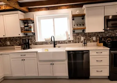 a kitchen with white cabinets and a sink and a window at Valley View Cabin in Morris