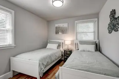 two beds in a bedroom with two windows at Renovated 2 BR home close to Lancaster attractions in Lancaster