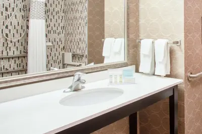 a bathroom with a sink and a mirror and towels at Hampton Inn Philadelphia/Voorhees in Voorhees