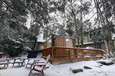 a deck with chairs in the snow in front of a house at Family retreat, Closest Rental House to POOL & BEACH, Hot tub, Game Room in Tobyhanna