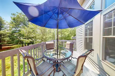 a table and chairs on a porch with an umbrella at Northridge 197 in Tannersville