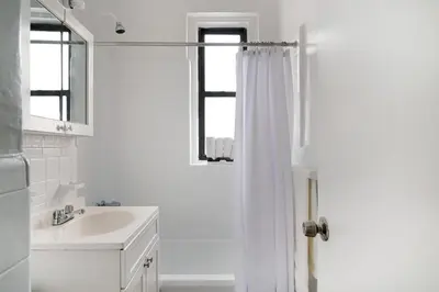 a white bathroom with a shower curtain and a sink at 105 -5G Brand New Studio prime location Elevator in New York