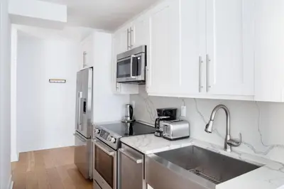 a kitchen with white cabinets and a stainless steel sink at Midtown East 2br w gym wd nr Grand Central NYC-1146 in New York