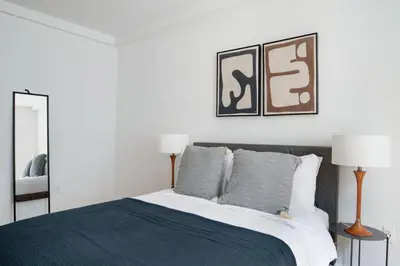 a bedroom with a bed and two lamps and a mirror at Midtown East 2br w gym wd nr Grand Central NYC-1146 in New York