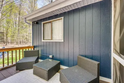 a porch with two wicker chairs and a blue wall at Deck and Community Perks Bright Pocono Lake Home! in Pocono Lake