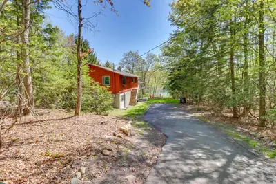 a road leading to a red house in the woods at Swim Dock and Game Room Lakefront Poconos Cabin! in Long Pond