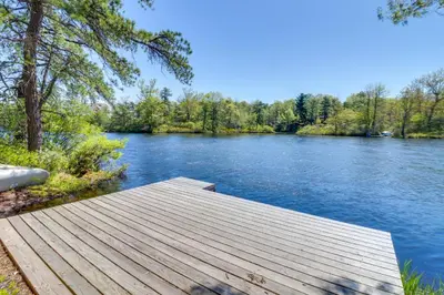 a wooden dock on a river with trees at Swim Dock and Game Room Lakefront Poconos Cabin! in Long Pond