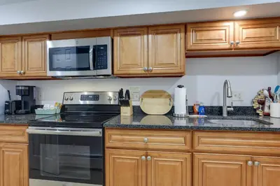 a kitchen with wooden cabinets and a stove and microwave at Quakertown Vacation Rental Close to Hiking Trails in Quakertown