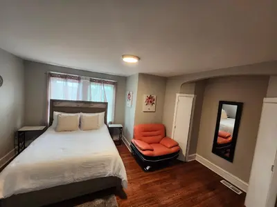 a bedroom with a bed and an orange chair at Comfy & Cozy in East Lansdowne