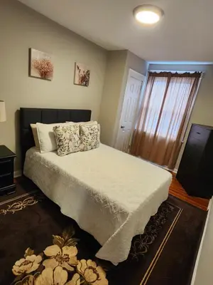 a bedroom with a bed with white sheets and a window at Comfy & Cozy in East Lansdowne