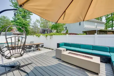 a patio with a couch and a table and an umbrella at Gorgeous Keansburg Home with Pool Walk to Beach! in Keansburg