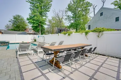 a patio with a wooden table and chairs next to a fence at Gorgeous Keansburg Home with Pool Walk to Beach! in Keansburg