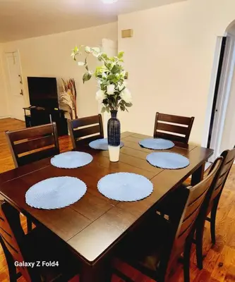 a wooden table with chairs and a vase of flowers on it at Cozy 1 Bedroom Business Suite in Philadelphia