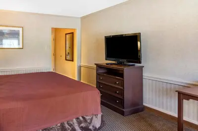 a hotel room with a bed and a flat screen tv at The Riverstone Inn in Towanda