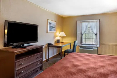 a hotel room with a bed and a flat screen tv at The Riverstone Inn in Towanda