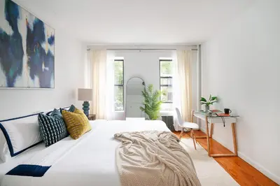 a white bedroom with a large bed and a desk at 444-3E Contemporary 1BR in Hell's Kitchen in New York