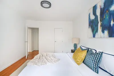a white bed with blue and yellow pillows on it at 444-3E Contemporary 1BR in Hell's Kitchen in New York