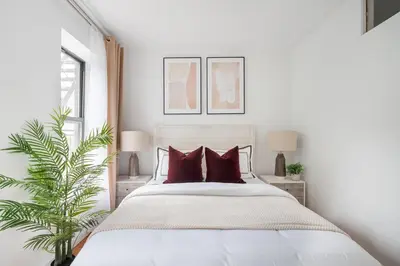 a white bedroom with a large bed with red pillows at 444-3E Contemporary 1BR in Hell's Kitchen in New York