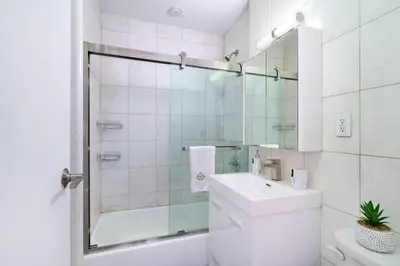a white bathroom with a shower and a sink at 444-3E Contemporary 1BR in Hell's Kitchen in New York