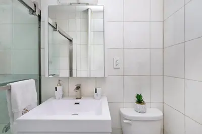 a bathroom with a sink and a toilet and a mirror at 444-3E Contemporary 1BR in Hell's Kitchen in New York