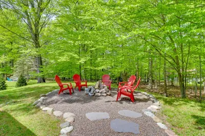 a group of red chairs sitting around a fire pit at Private Hot Tub and Fire Pit Pocono Lake House! in Pocono Lake
