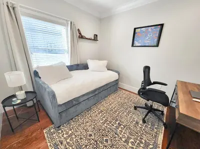 a bedroom with a couch and a desk and a chair at SkyHouse JC - New 3BR Apt with Private Rooftop in Jersey City