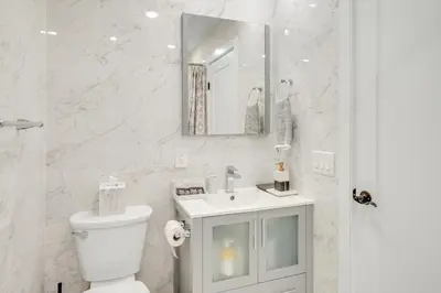 a bathroom with a toilet and a sink and a mirror at SkyHouse JC - New 3BR Apt with Private Rooftop in Jersey City