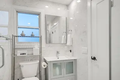 a white bathroom with a toilet and a sink at SkyHouse JC - New 3BR Apt with Private Rooftop in Jersey City