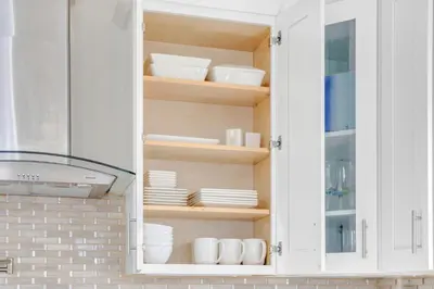a white cabinet with plates and dishes in it at SkyHouse JC - New 3BR Apt with Private Rooftop in Jersey City