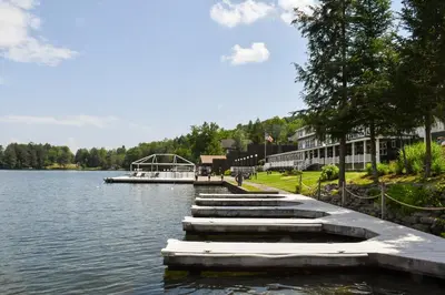 a dock on a lake with a boat in the water at Chestnut Inn at Oquaga Lake in Deposit